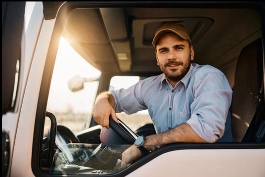 man wearing hat sitting in the drivers seat of a semi truck